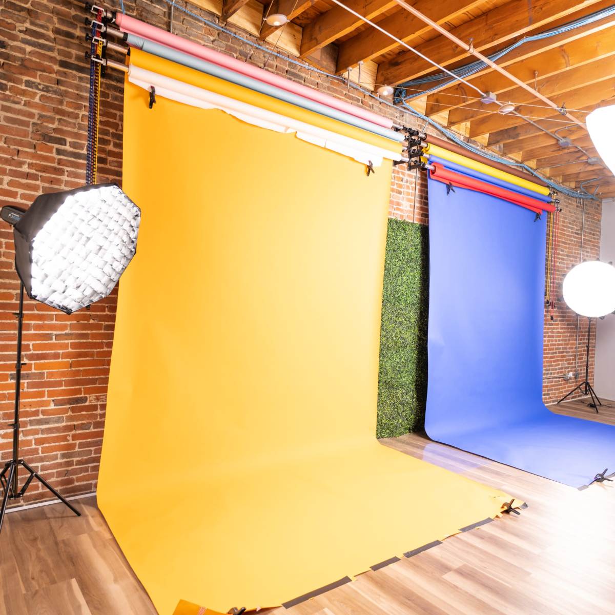 A photography studio with yellow, blue, and green backdrops, along with lighting equipment set up for a photo shoot.
