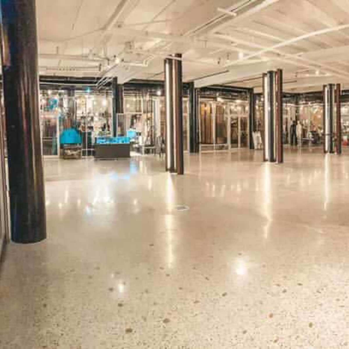 A spacious, industrial-style interior with polished concrete floors and numerous glass partitions.