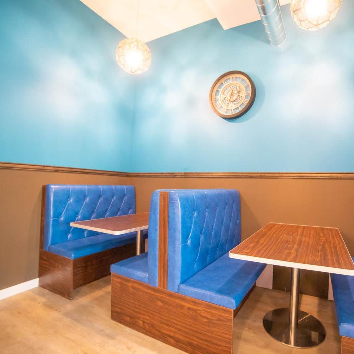 A small dining area with two blue upholstered booths and a wooden table against a blue and brown wall.