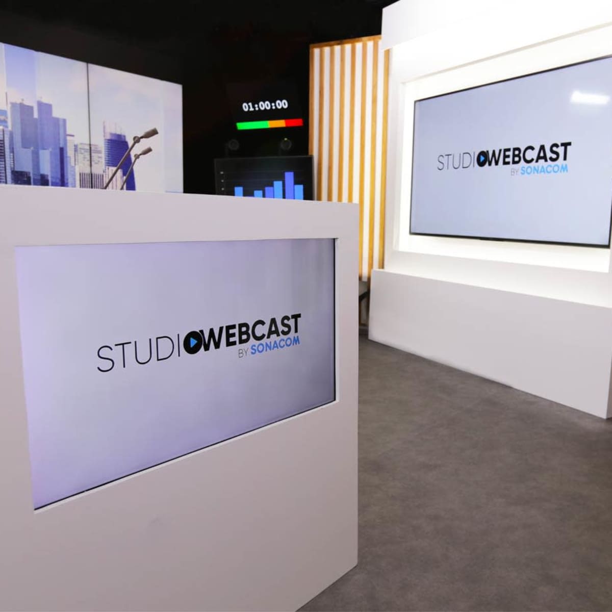 A modern studio setup with large screens displaying the logo "STUDIO WEBCAST by SONACOM."