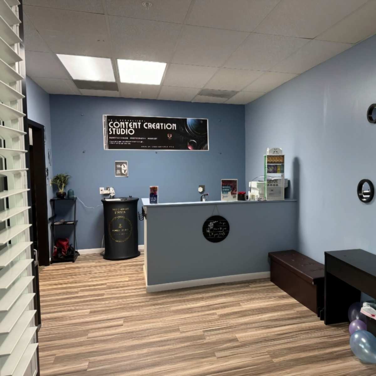 The interior of a content creation studio featuring a reception area with a desk, promotional signage, and decorative elements on the walls.