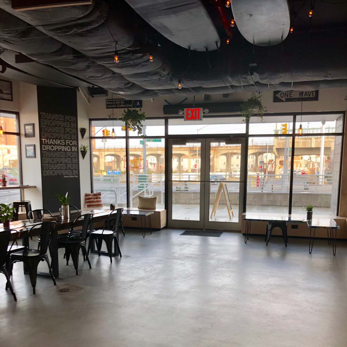 A spacious café interior with seating arrangements and large glass doors leading to an outdoor area.