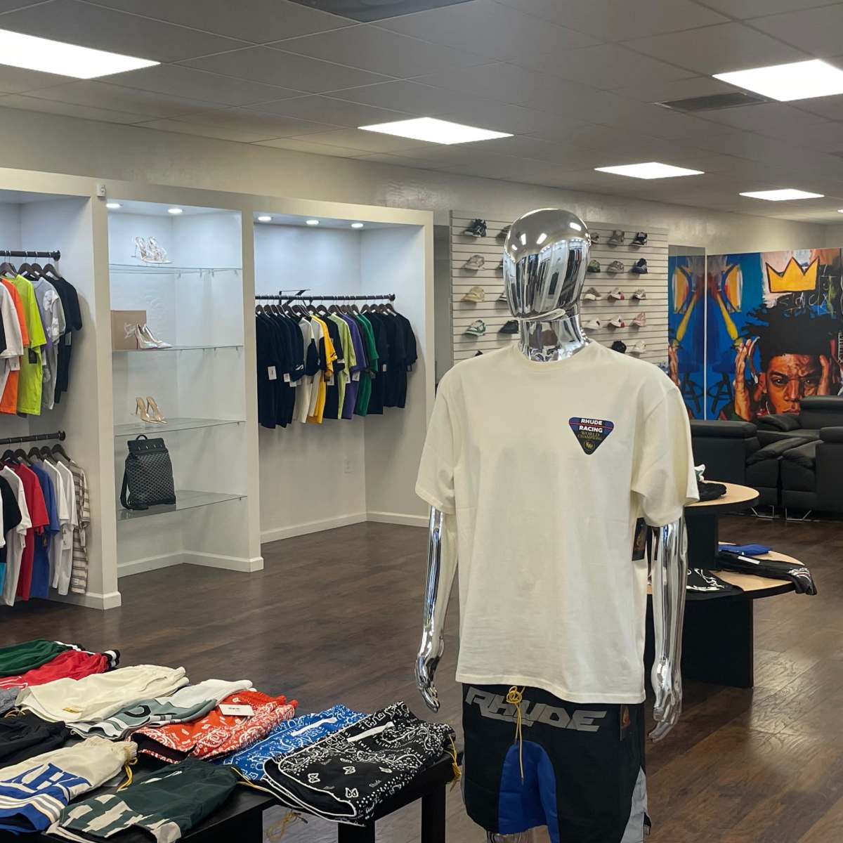 A clothing store interior featuring shelves of neatly arranged shirts and accessories, with mannequin displays in the foreground.