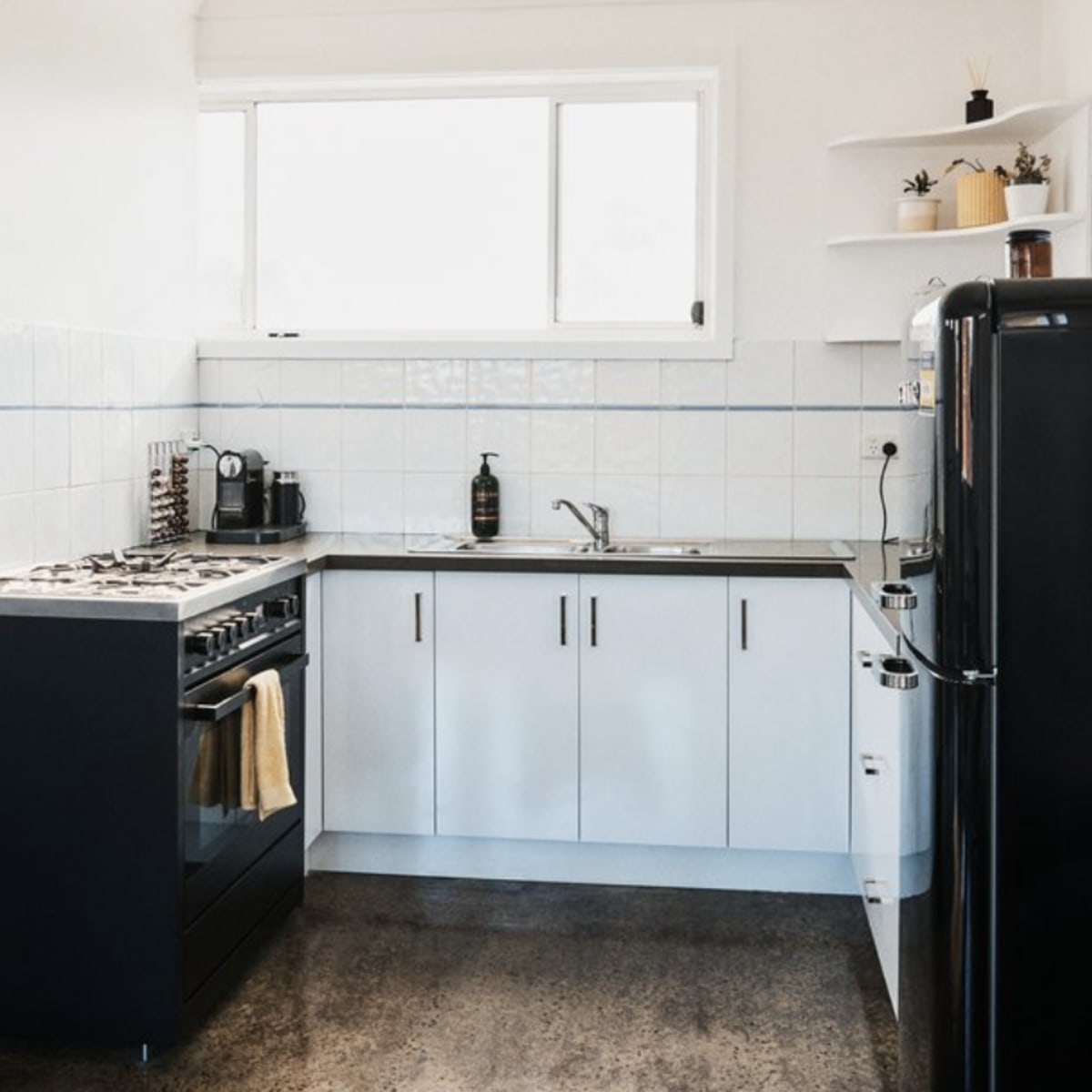 A modern kitchen with a gas stove, a stainless steel sink, and black and white cabinetry.
