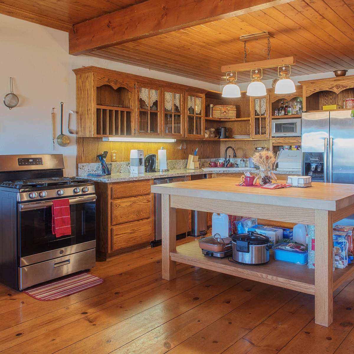 A spacious kitchen features wooden cabinetry, a central island, stainless steel appliances, and a warm, inviting atmosphere.