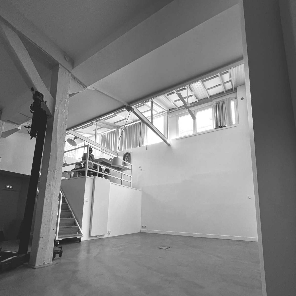 An empty, spacious indoor area with high ceilings and large windows providing natural light.