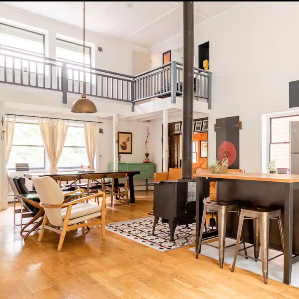 A modern open-concept kitchen and dining area with wood flooring, featuring a central island and a dining table.