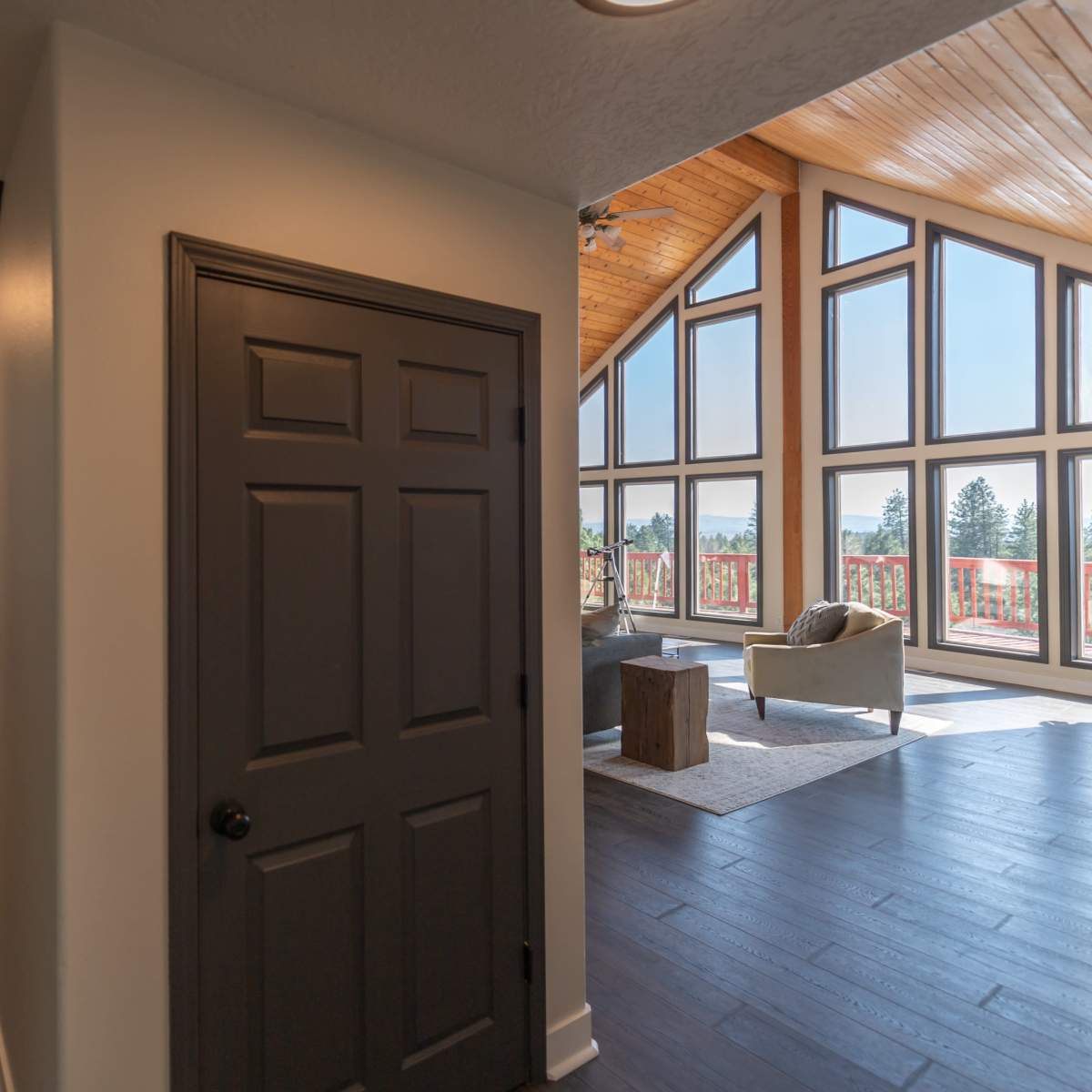 A hallway leads to a spacious room with large windows that provide a view of the outdoors.