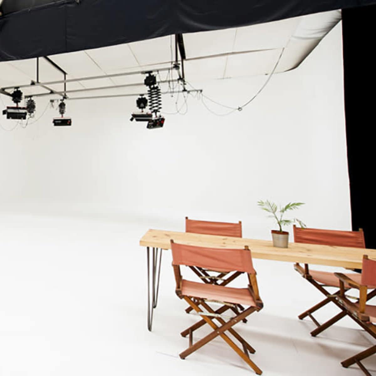 A spacious, minimally decorated studio with white walls, a clean floor, and a wooden table set with chairs.