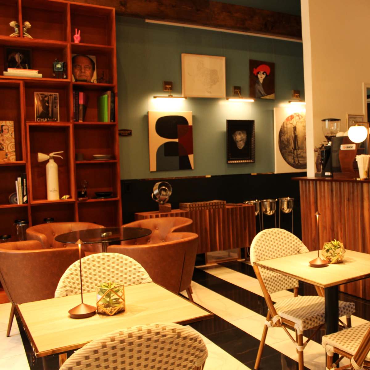 A contemporary café interior with wooden shelves, seating areas, and a display counter for beverages.