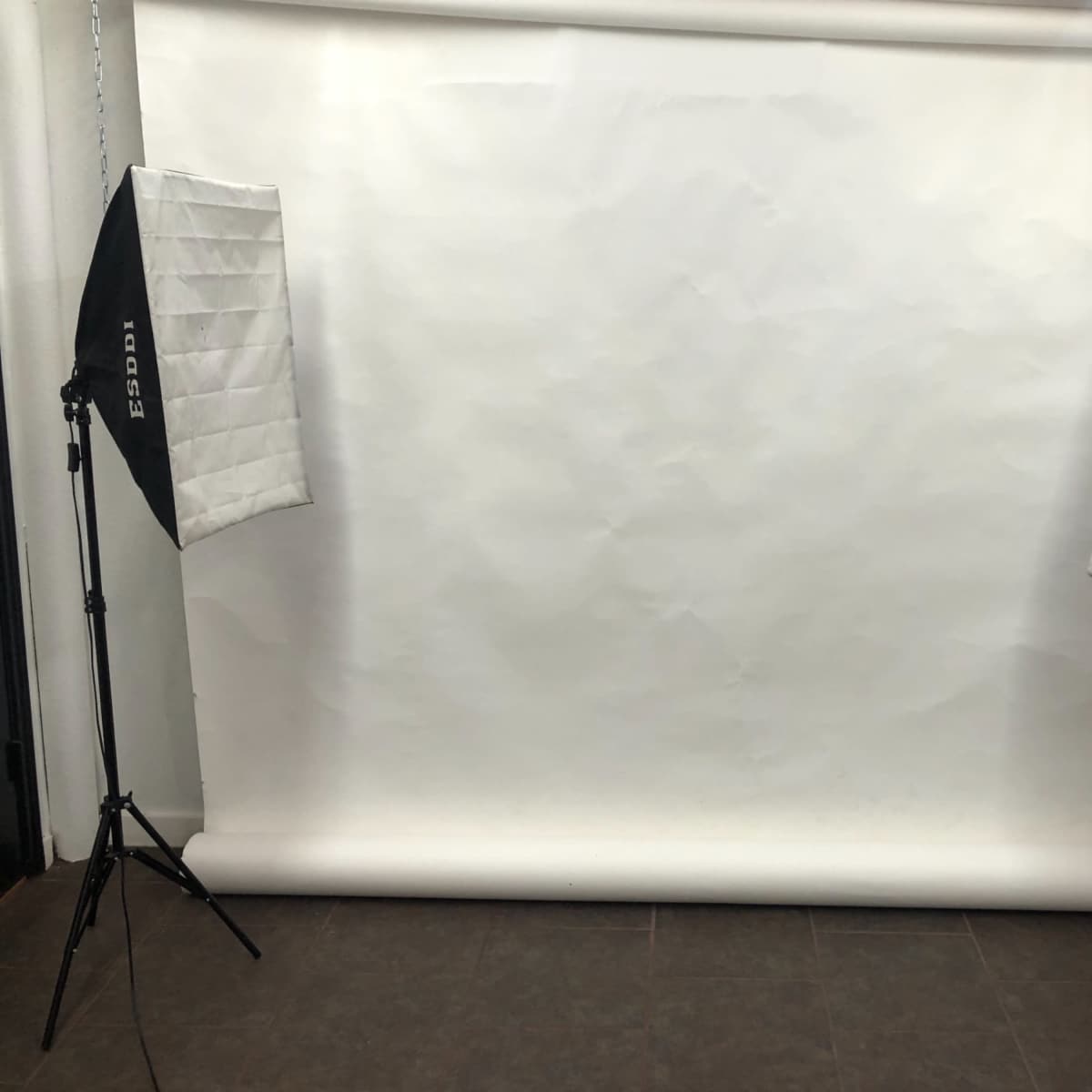 A photography studio setup with two softbox lights positioned on either side of a plain white backdrop.