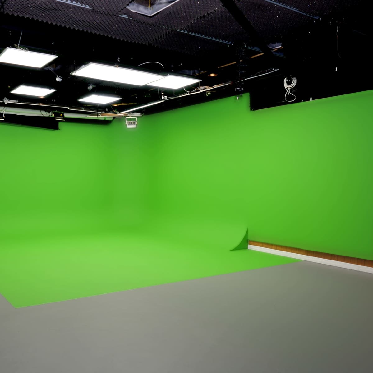 A studio space equipped with green screens on the walls and floor.