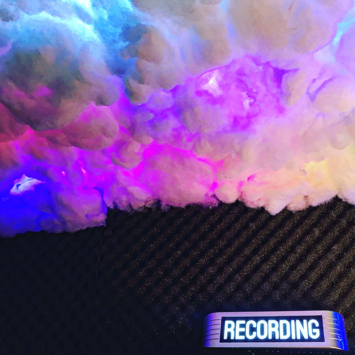 A colorful cloud-like installation is positioned above a rectangular sign that reads "RECORDING."