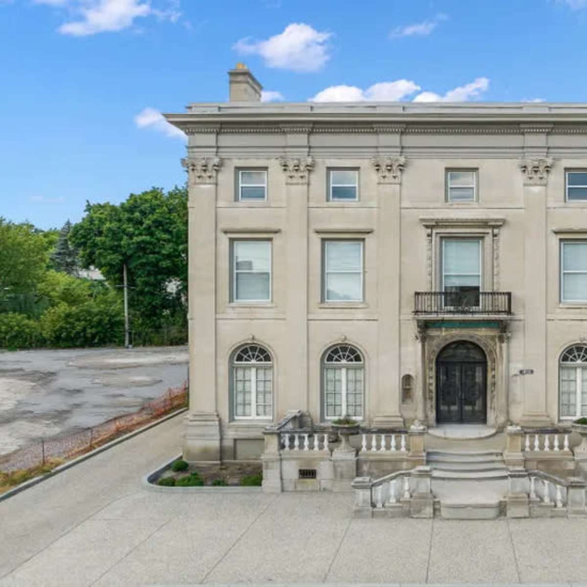 A large, stately building with a symmetrical facade, featuring arched windows and a central entrance framed by steps and a balcony.