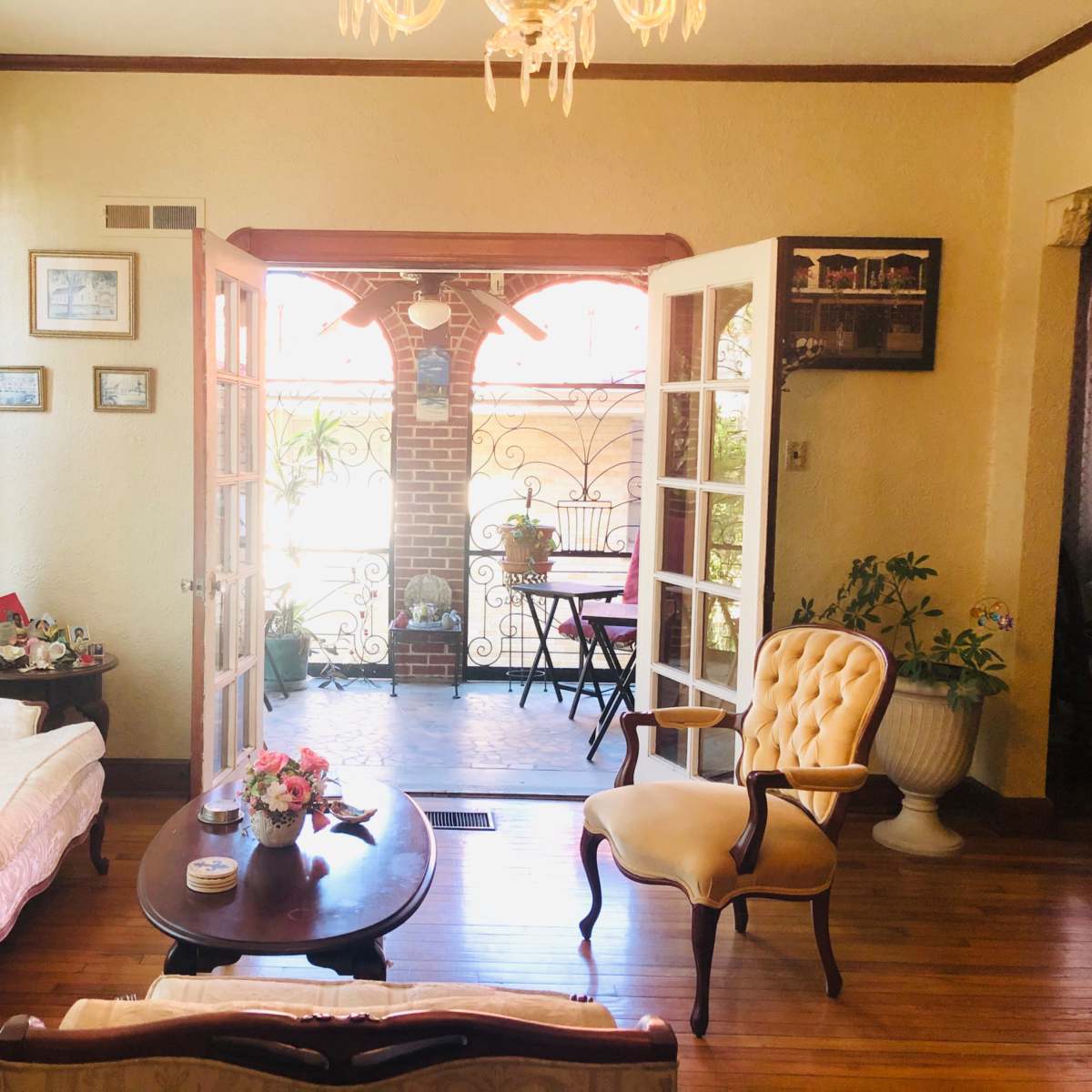 A well-furnished living room features a sofa, an armchair, and a coffee table, with doors leading to a small outdoor patio.