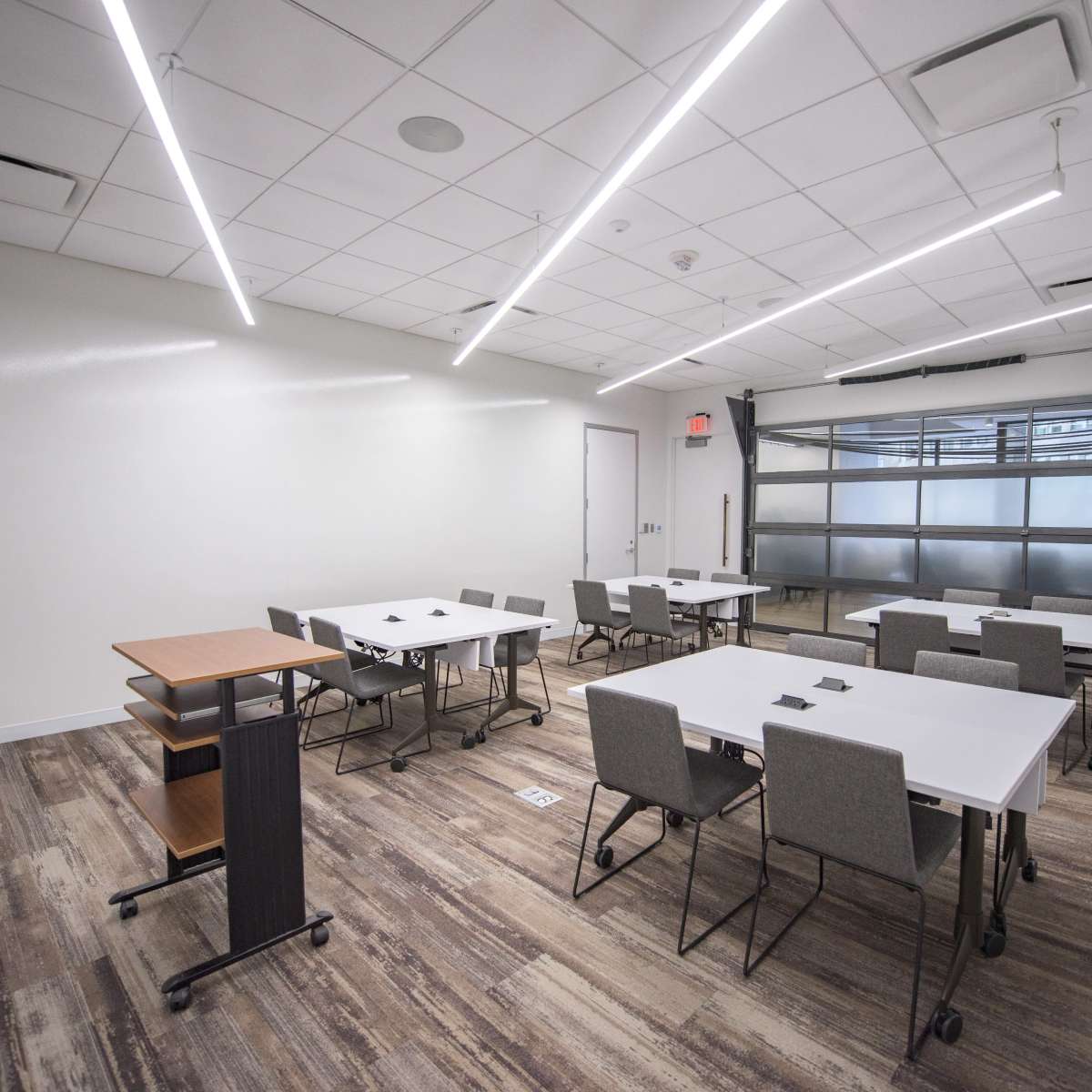 A modern classroom with multiple rectangular tables and chairs arranged in a spacious layout.