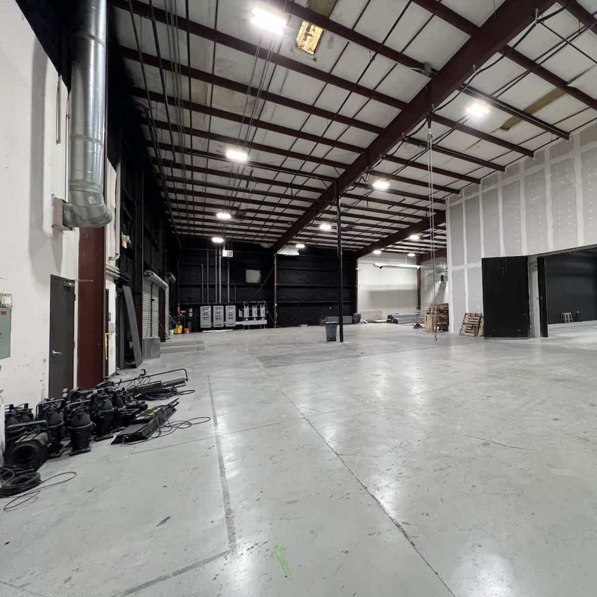 A spacious industrial warehouse with a concrete floor, exposed metal beams, and unfinished walls.