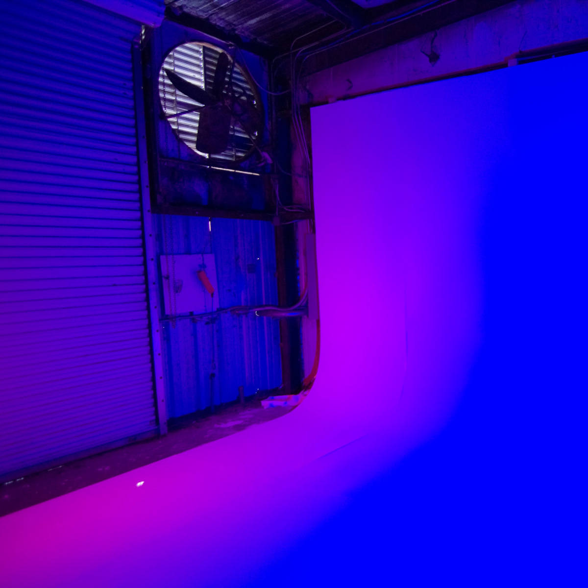 A studio space features a backdrop with a gradient transitioning from purple to blue.