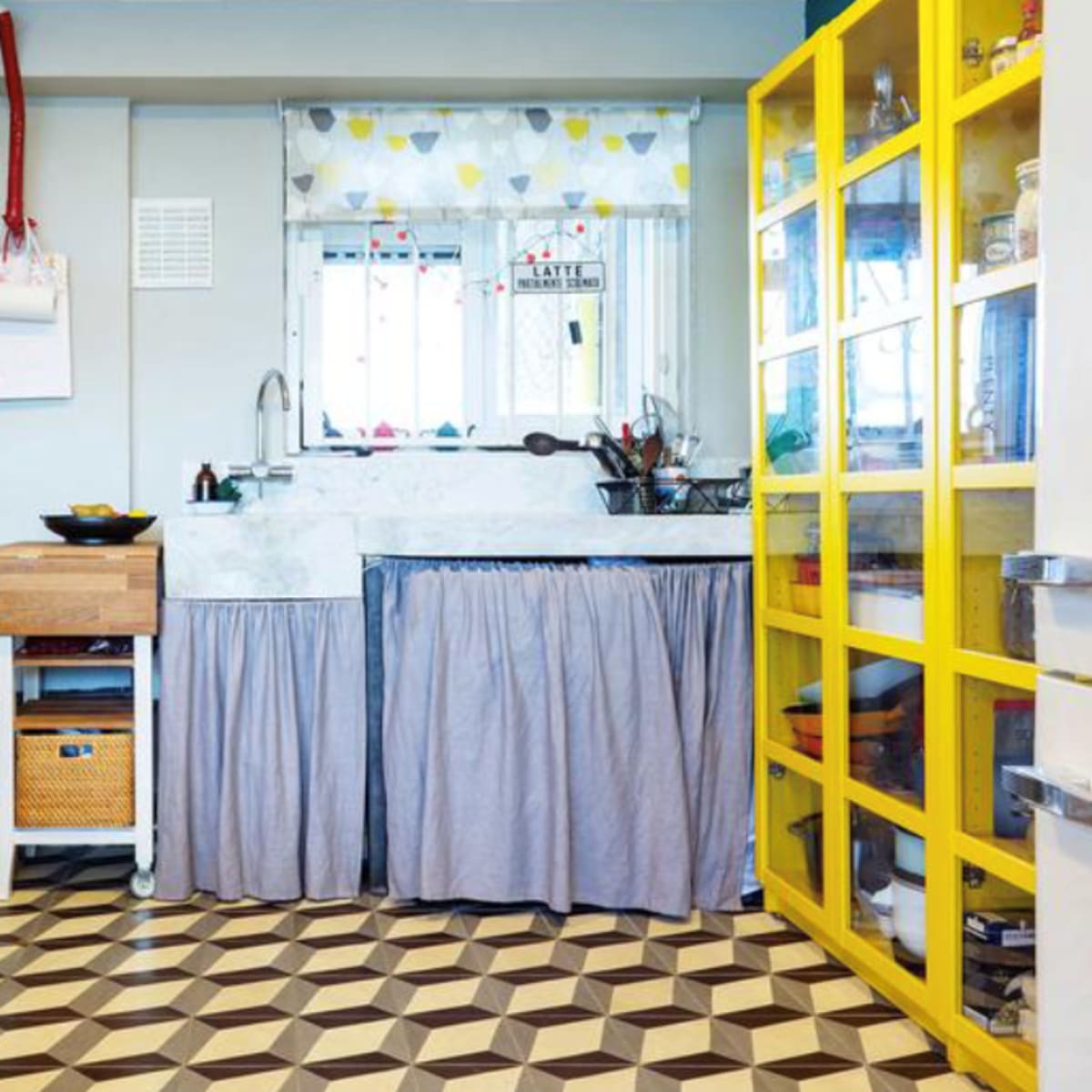 A compact kitchen featuring a two-tone color scheme with a black stove, a wooden storage unit, a marble countertop, and a bright yellow glass-door cabinet.