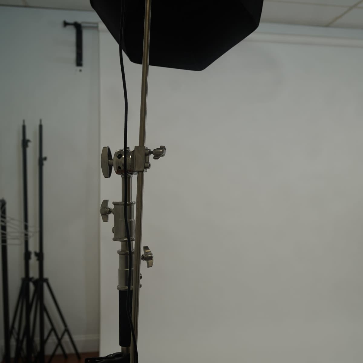 A photography studio setup featuring a backdrop, lighting equipment, and a folding chair.
