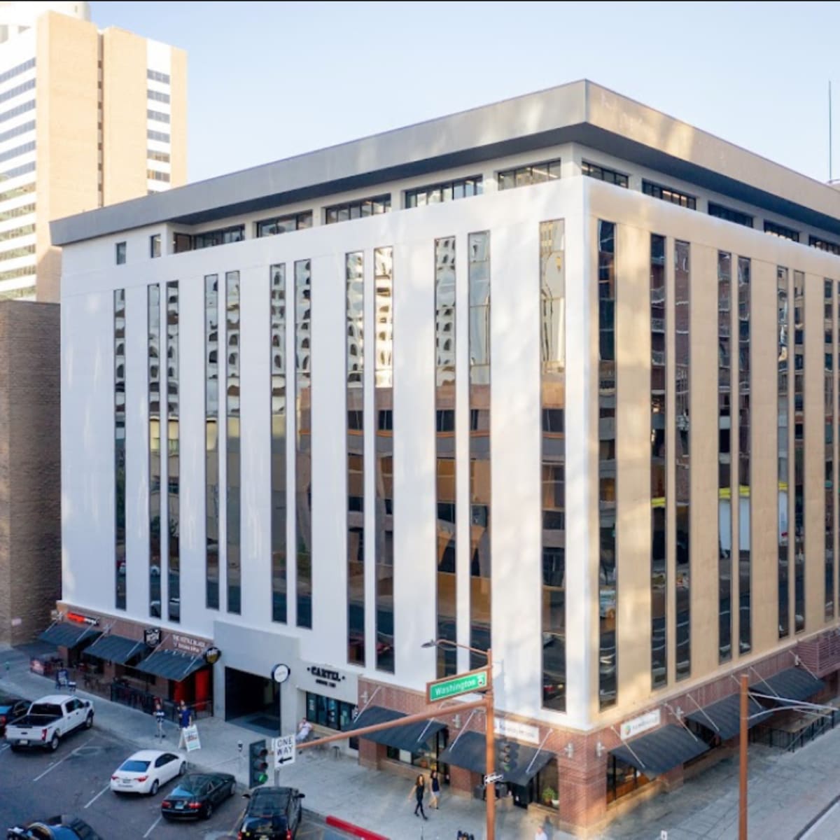 A multi-story building with large windows and a modern facade is situated at the intersection of two streets.