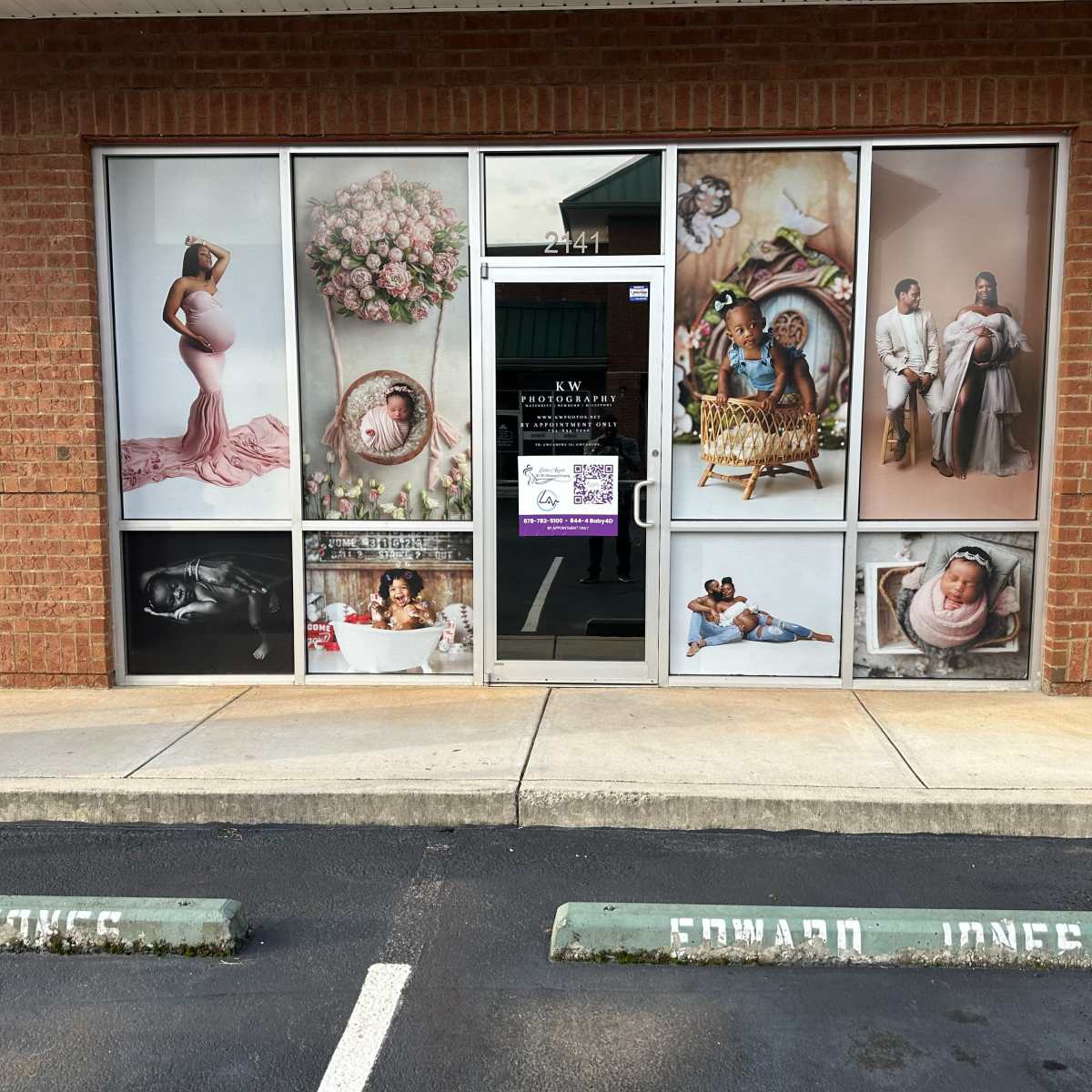 The storefront of a photography studio, featuring large photographs of pregnant women, families, and newborns displayed on its windows.