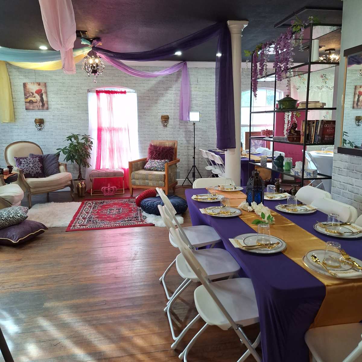 A decorated room with a dining table set for a meal, surrounded by plush seating areas and vibrant drapery.