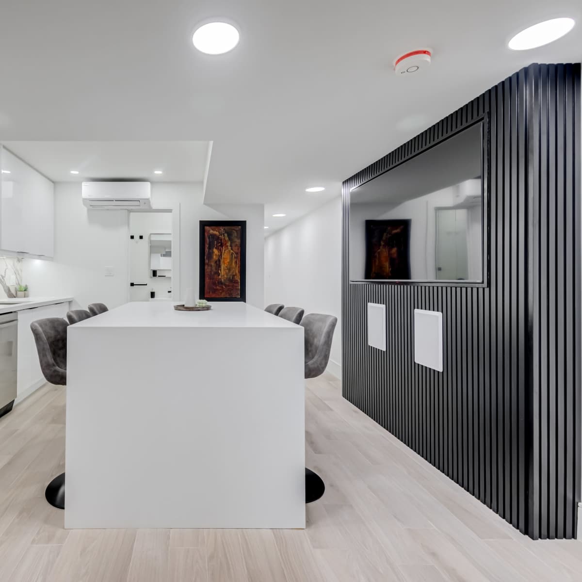 A modern kitchen features a central island with seating, stainless steel appliances, and sleek cabinetry against a marble backsplash.