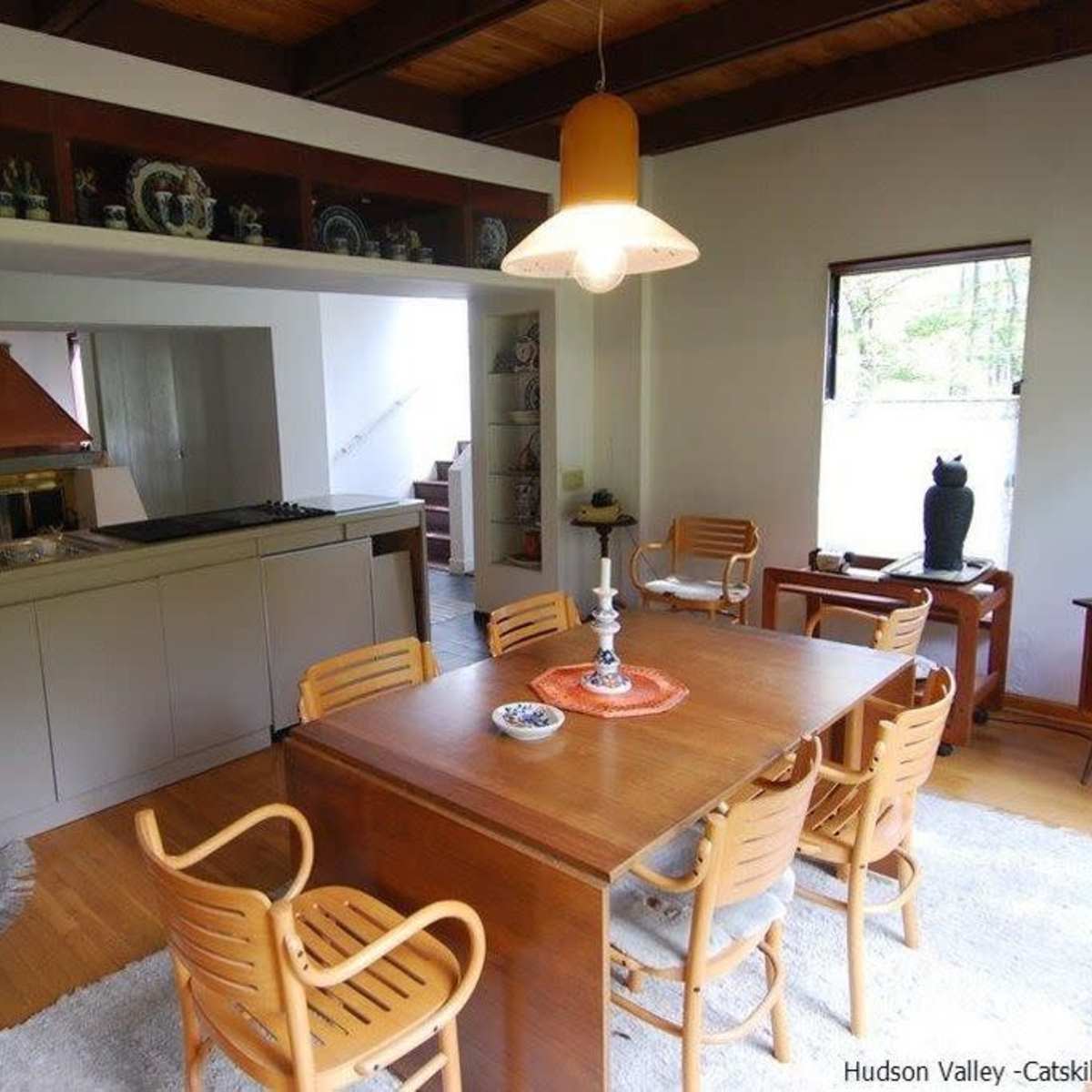 A kitchen and dining area featuring a wooden table surrounded by chairs, with a small kitchenette in the background.
