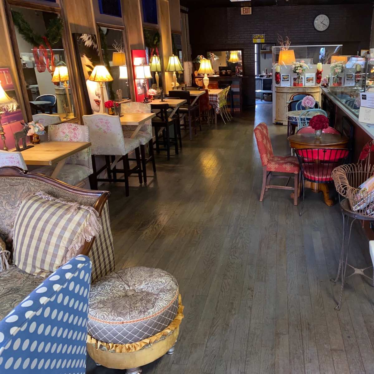 A cozy café interior with various seating areas, lamps, and decorative elements along the walls.