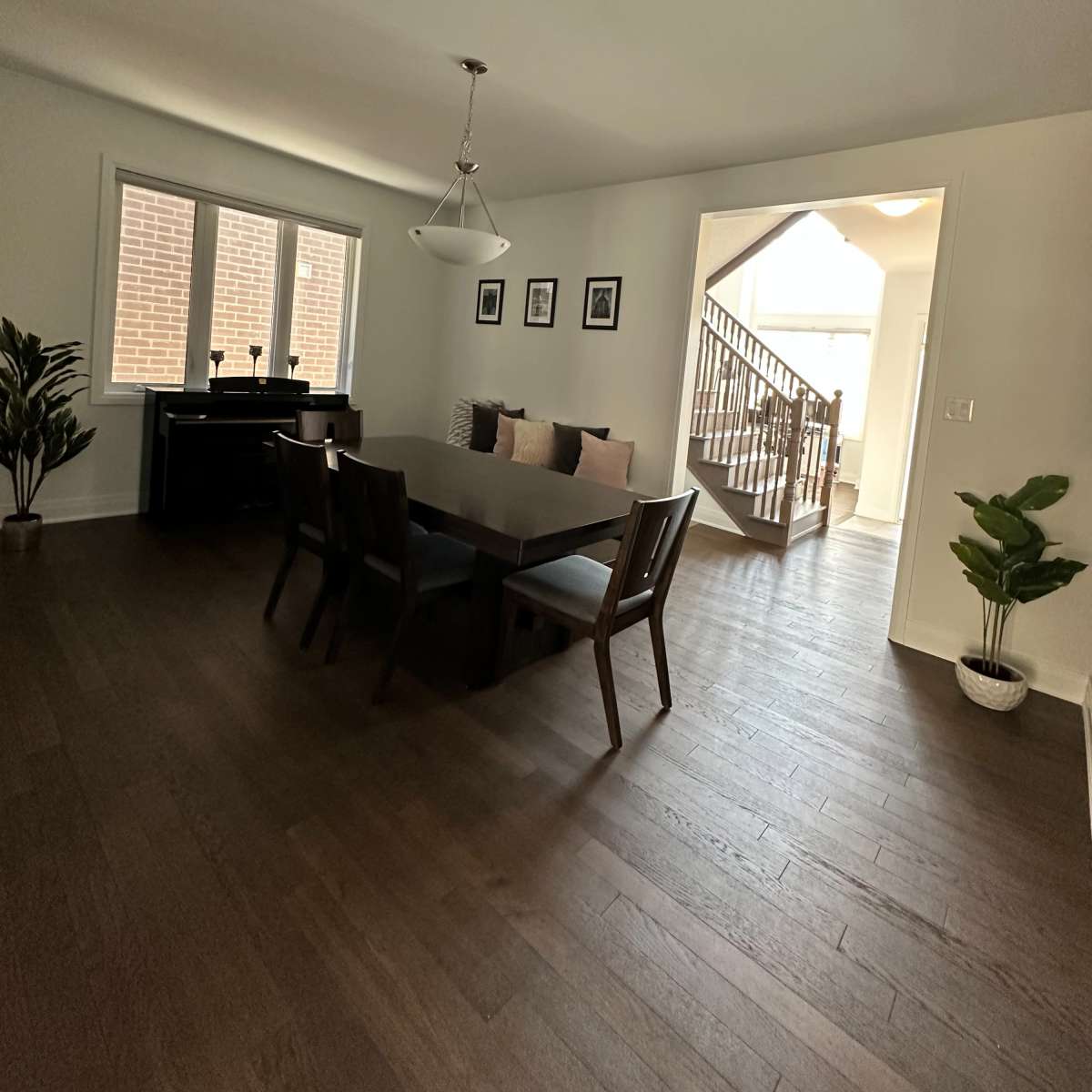 A dining area with a rectangular table surrounded by chairs, and a staircase leading to another level in the background.