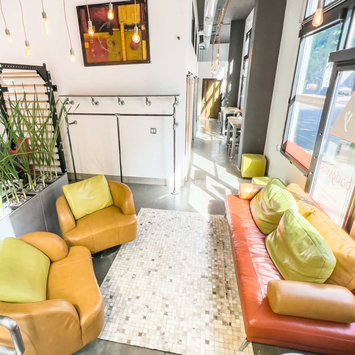 A modern seating area featuring two armchairs and a sofa, surrounded by indoor plants and large windows with natural light.