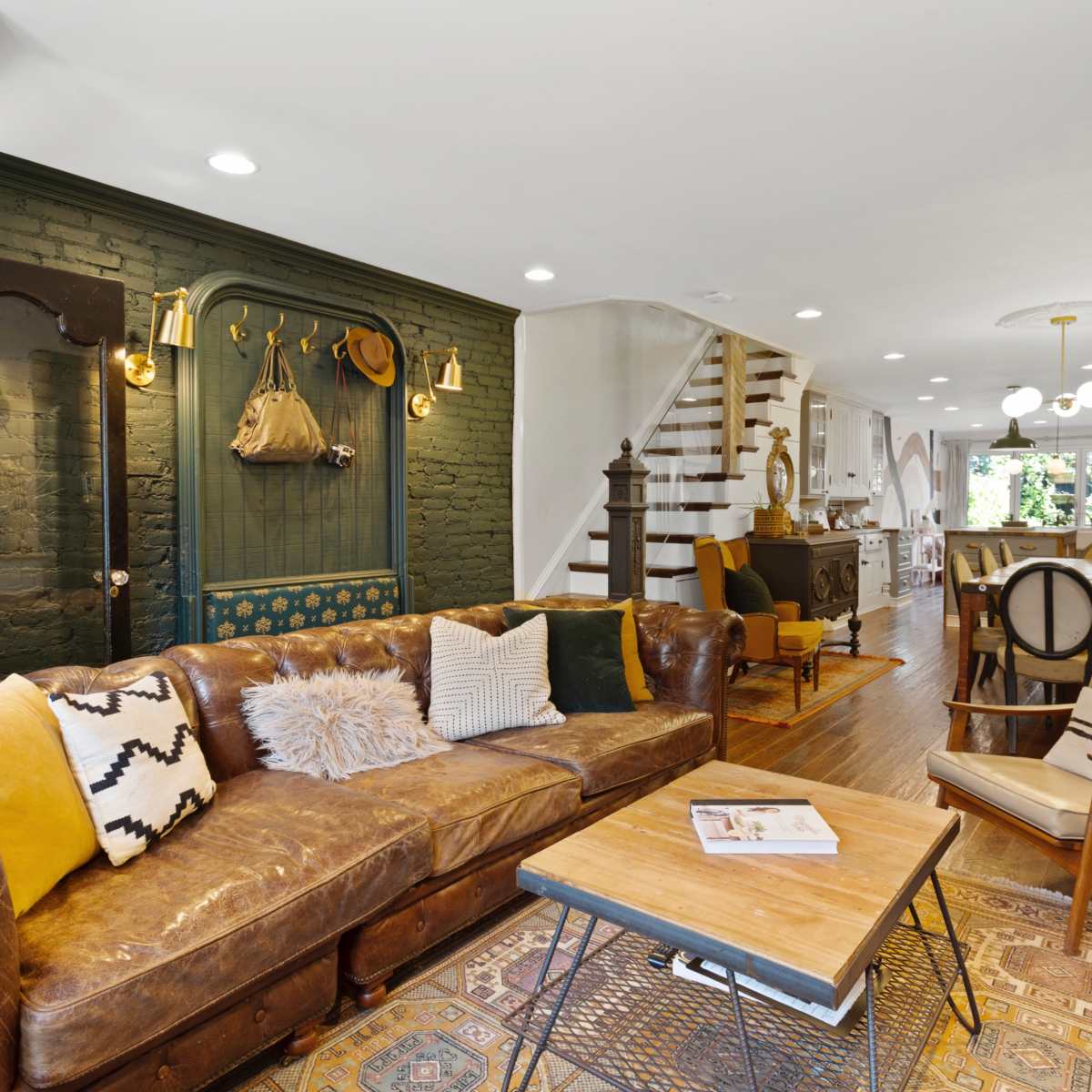 The room features a cozy living area with a brown leather sofa, a wooden coffee table, and a staircase leading to the upper level.