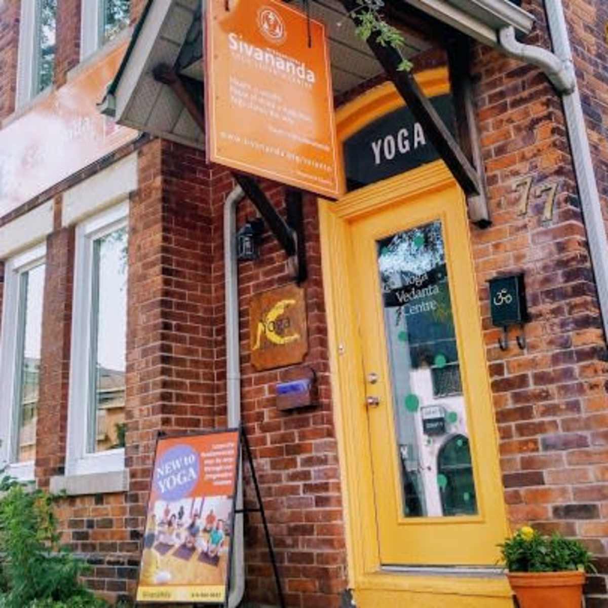 A brick building with bright orange signage marks the entrance to a yoga center called Sivananda.