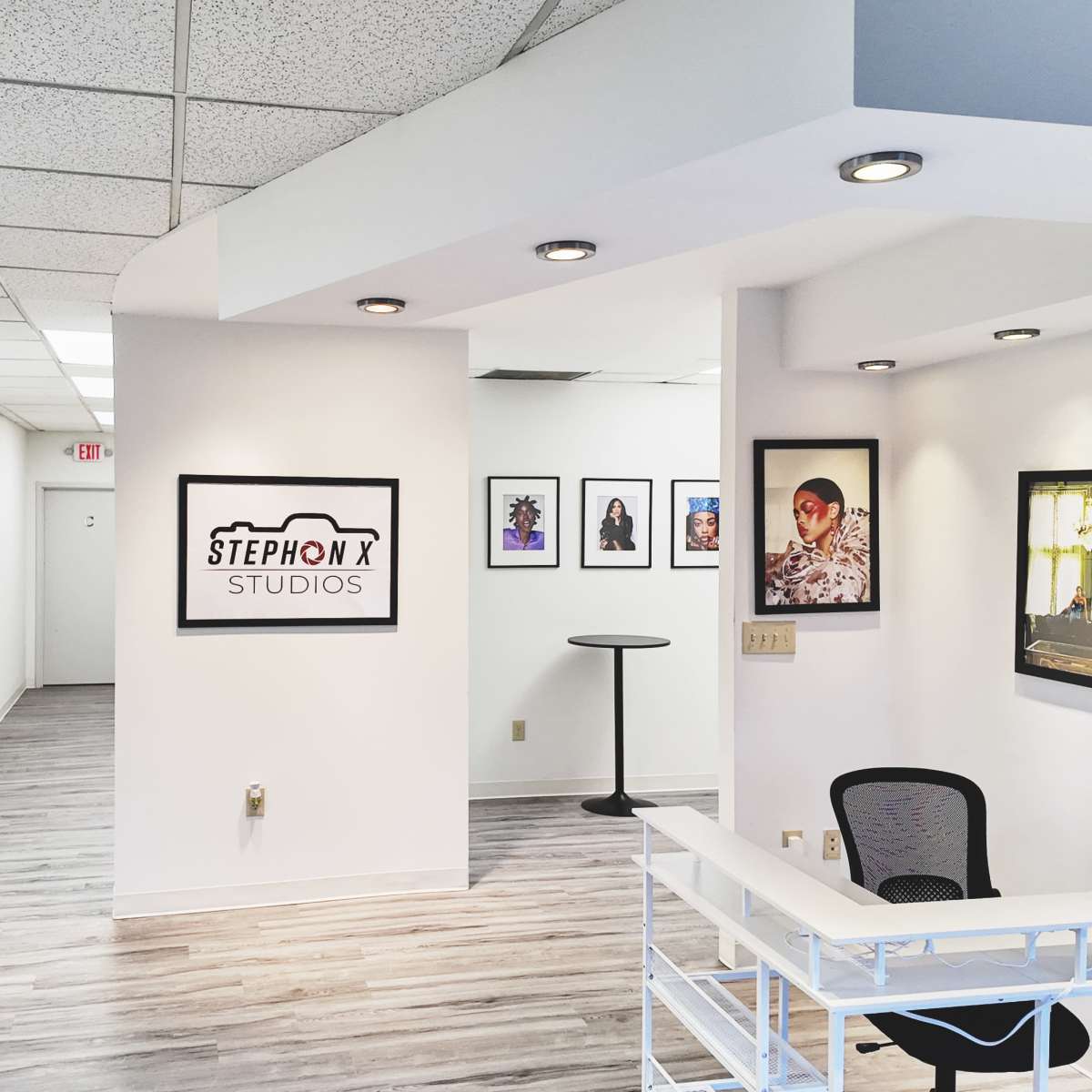 The interior of a photography studio with a reception area, framed photographs on the walls, and a visible hallway leading to other rooms.