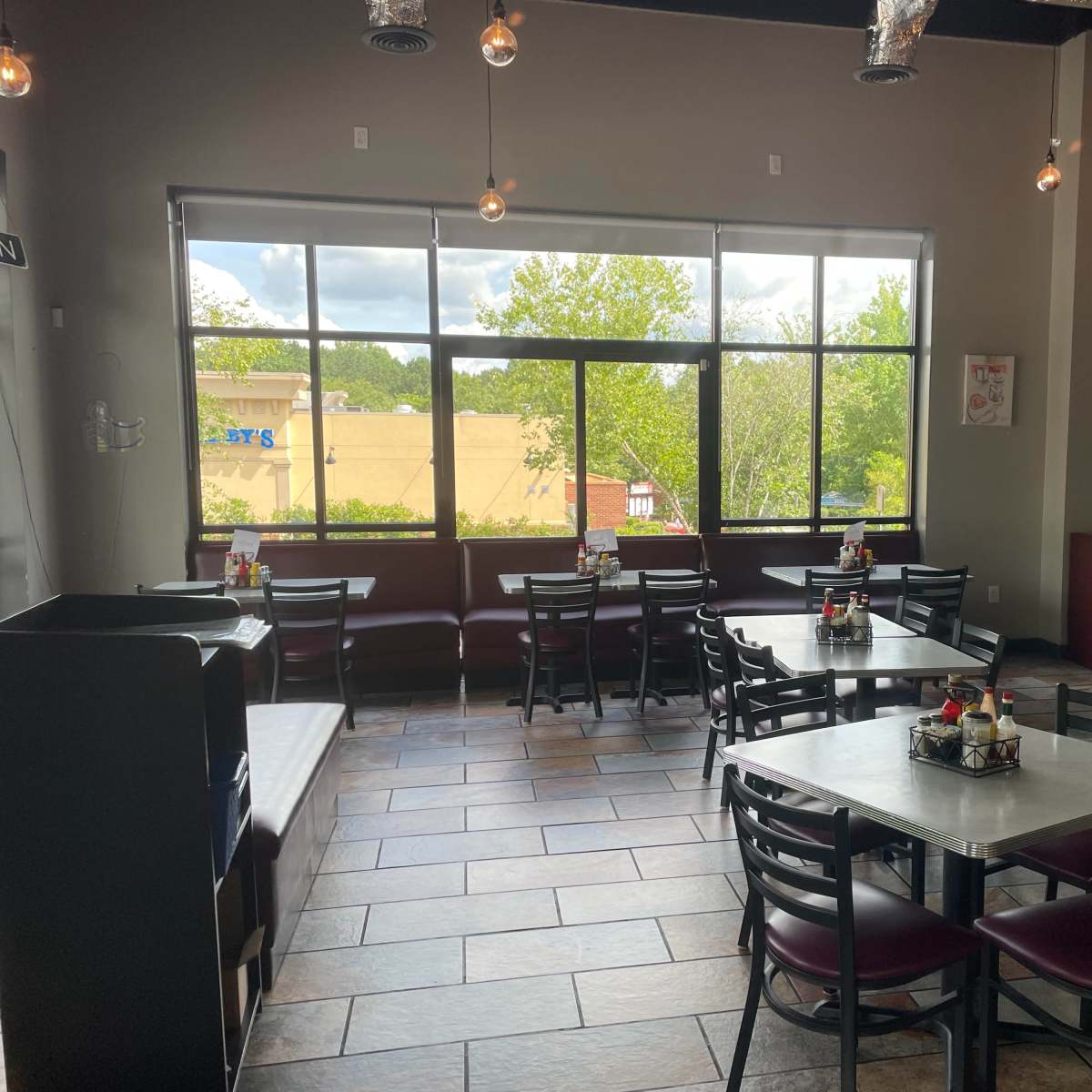 A dining area of a restaurant with several tables and chairs arranged around a large window that lets in natural light.