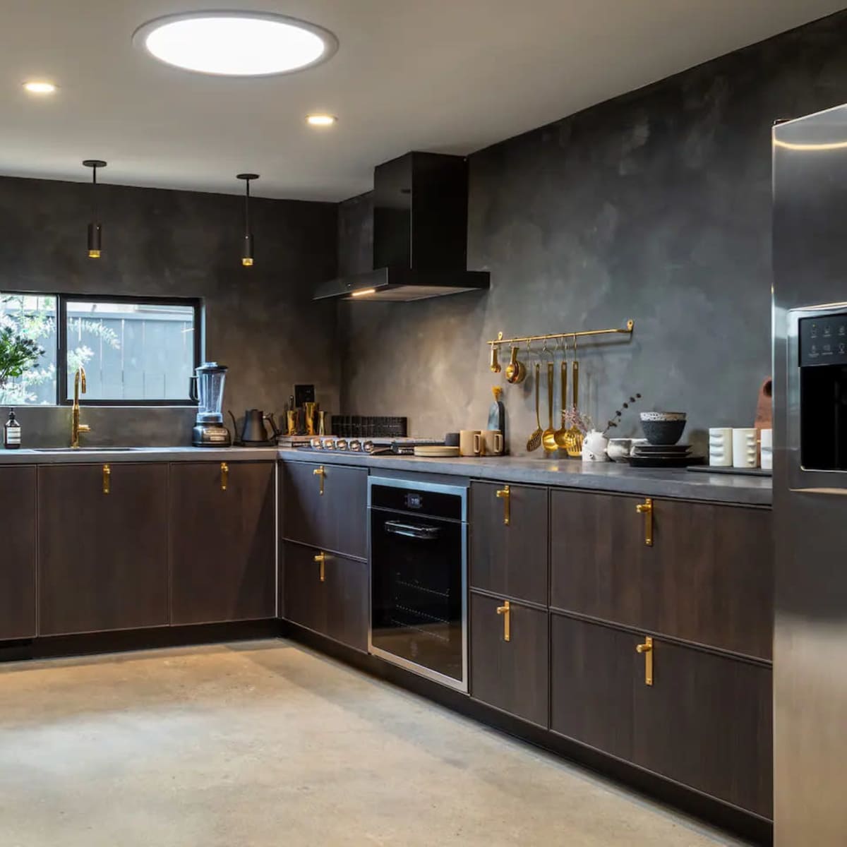 A modern kitchen featuring dark wood cabinetry, stainless steel appliances, and an island with a minimalist design.