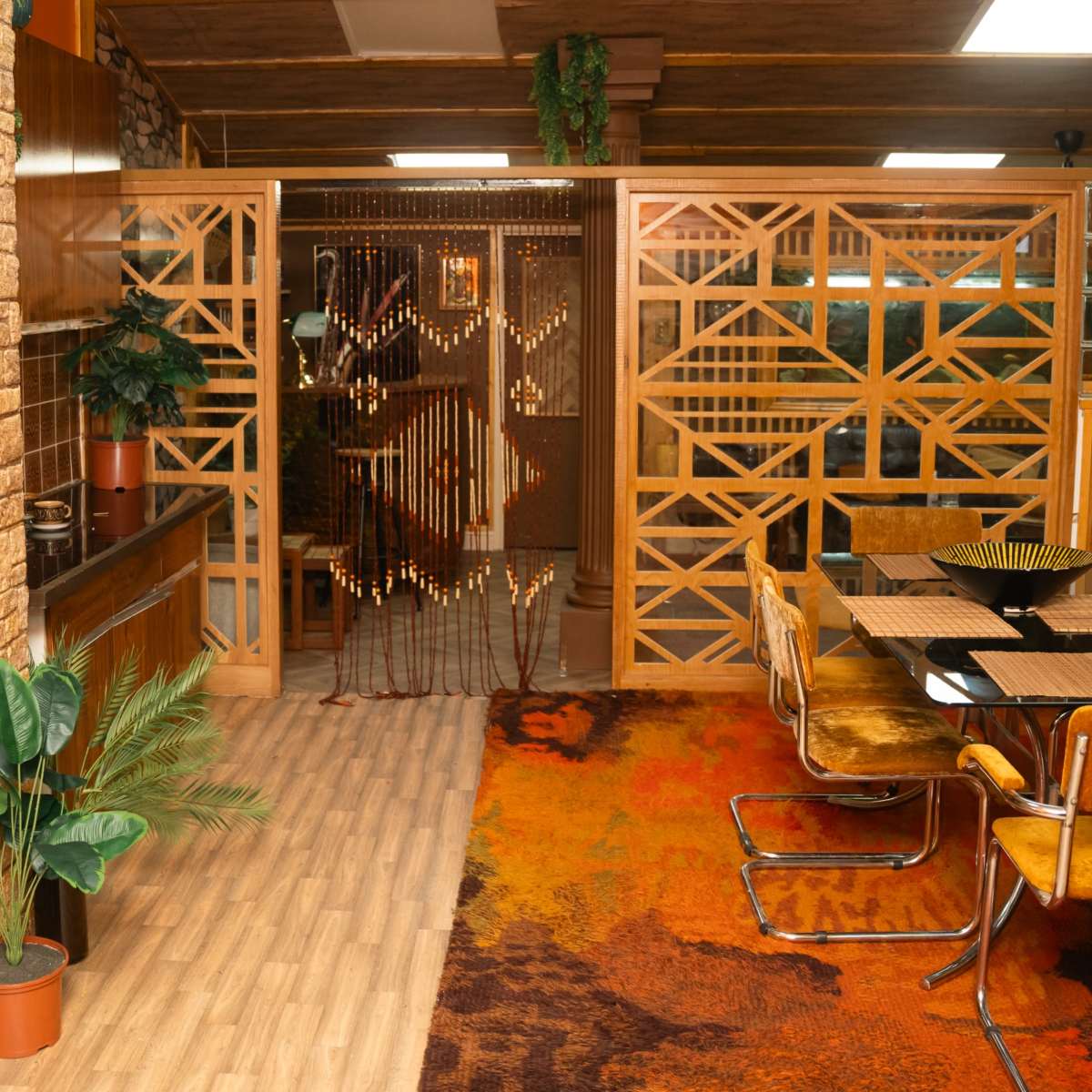 A cozy interior space featuring wooden paneling, a patterned rug, and a dining area with yellow chairs beside a wooden table.