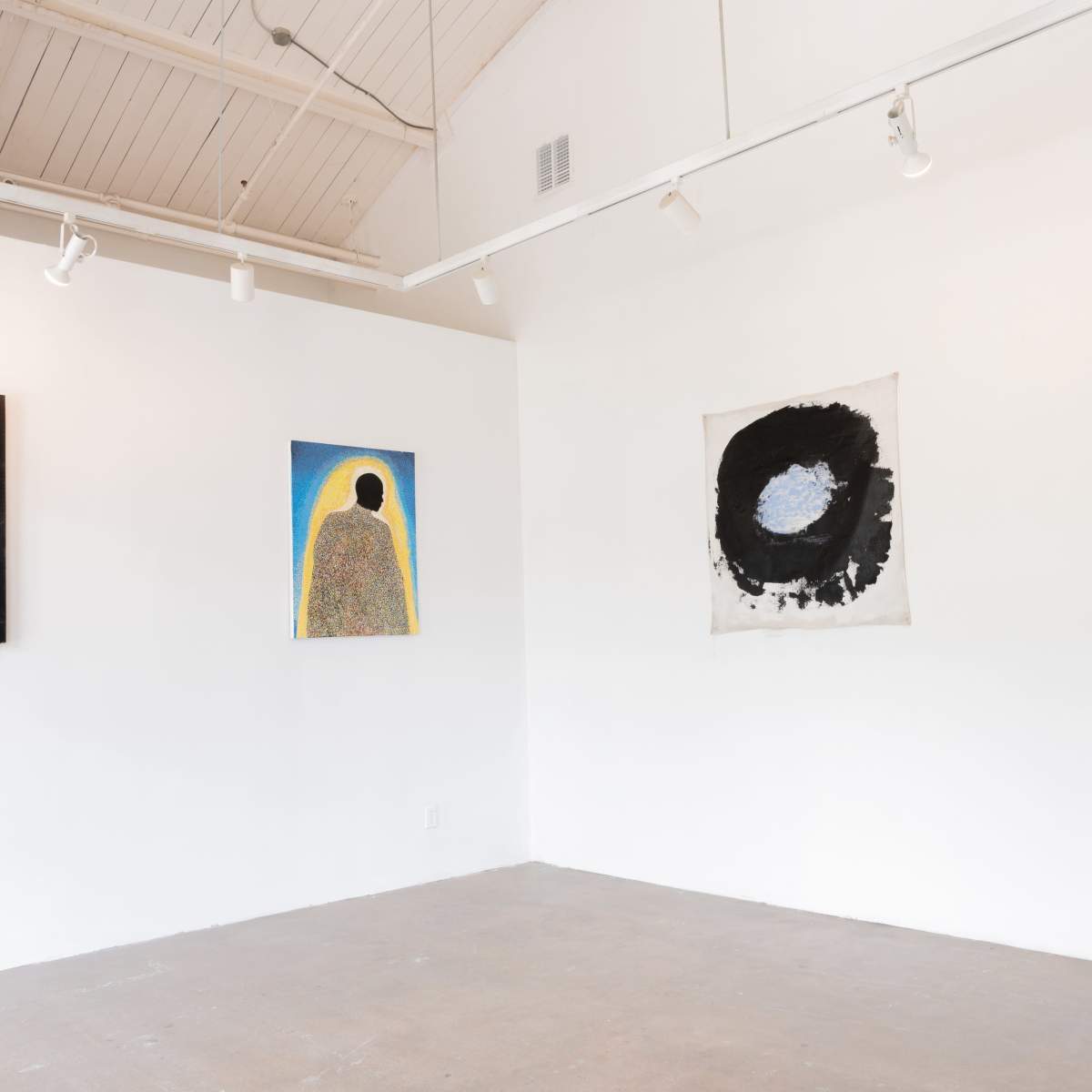 An art gallery with four paintings displayed on the white walls, featuring various abstract designs.