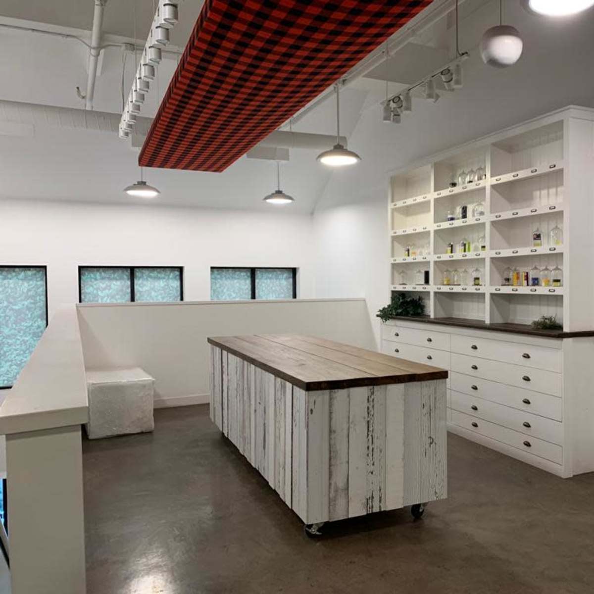 A modern interior space with a large wooden island, white cabinetry, and windows allowing natural light.