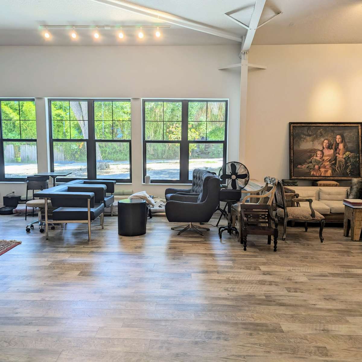 A spacious interior with a variety of furniture pieces arranged near large windows, providing ample natural light.