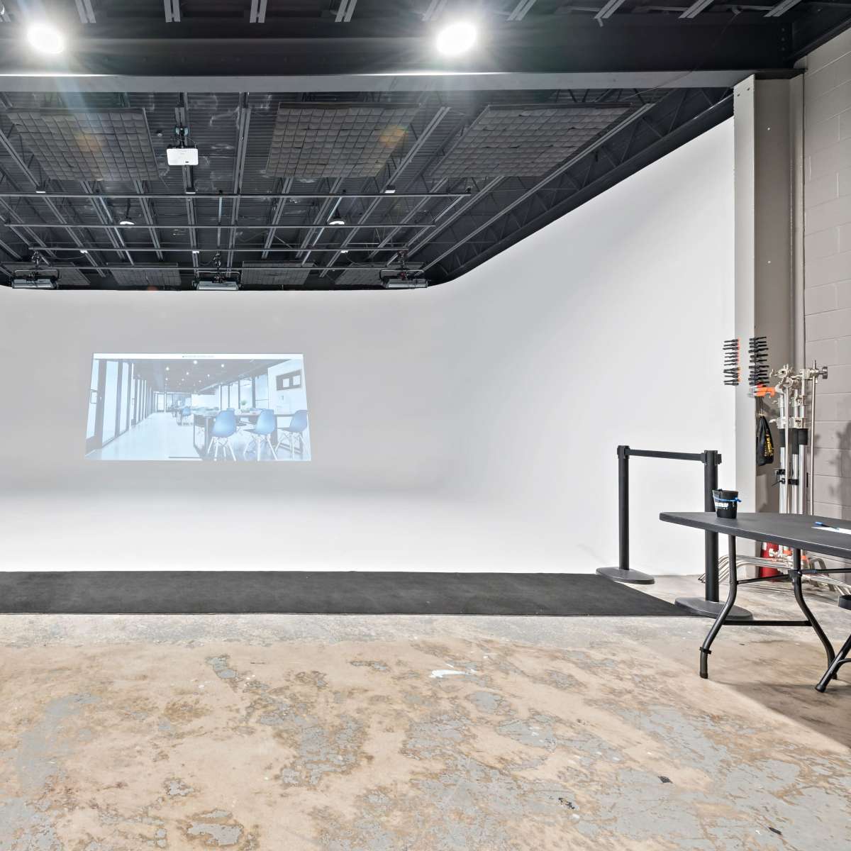 A spacious studio features a white backdrop with a projected grayscale image of an interior space.