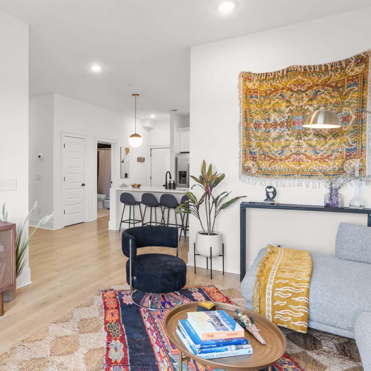 A modern living room with a television mounted on the wall, a patterned rug on the floor, and a cozy seating area, including a gray sofa and a round coffee table.