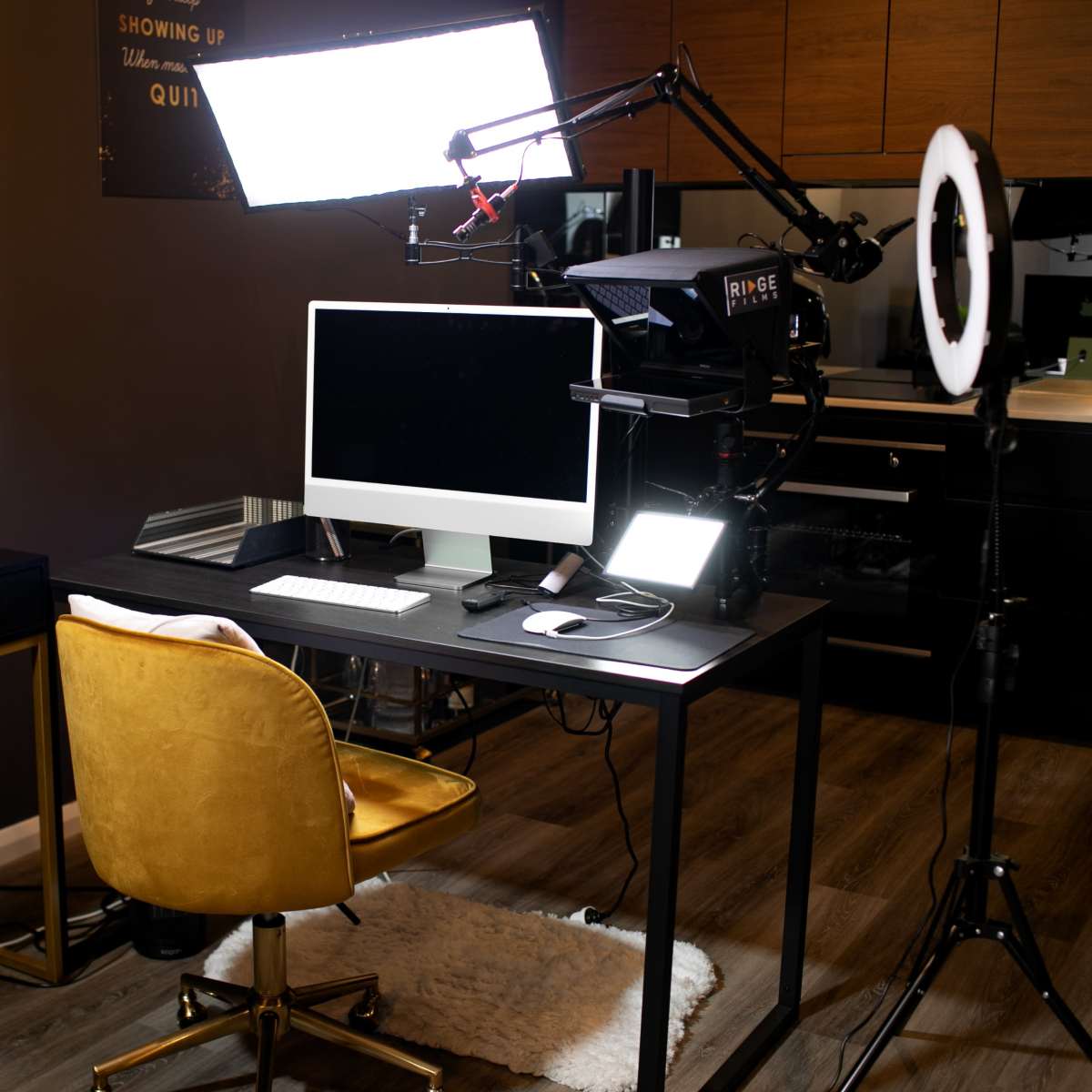 A modern workspace featuring a black desk with a computer, a yellow chair, and professional lighting equipment.