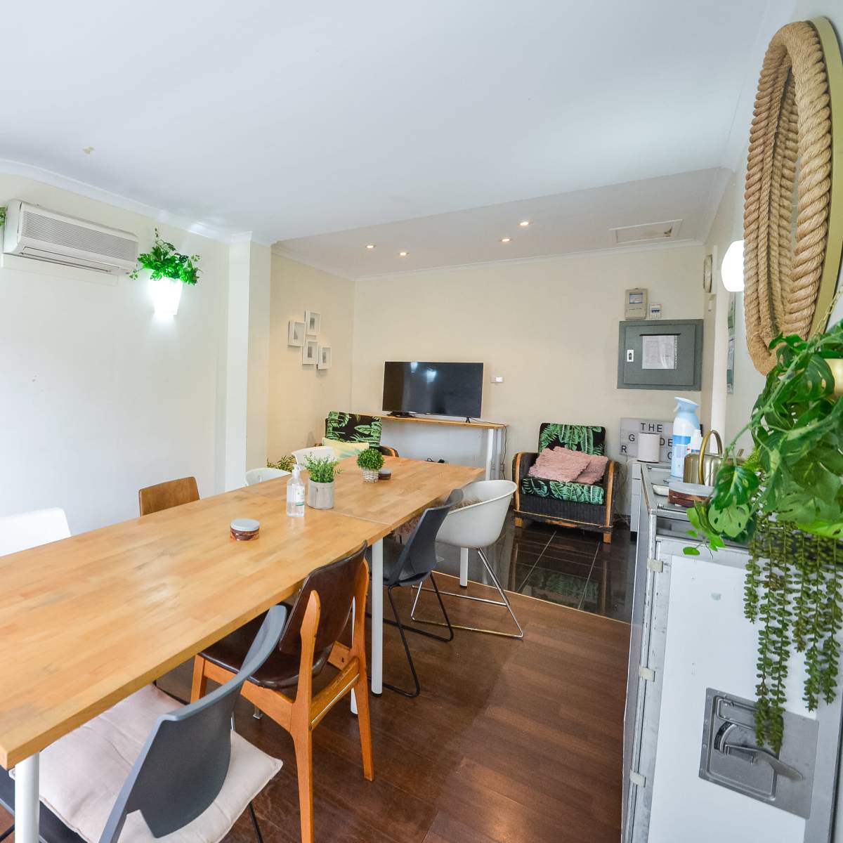 A bright, modern dining area featuring a wooden table with several chairs, a whiteboard, and a television on the wall.