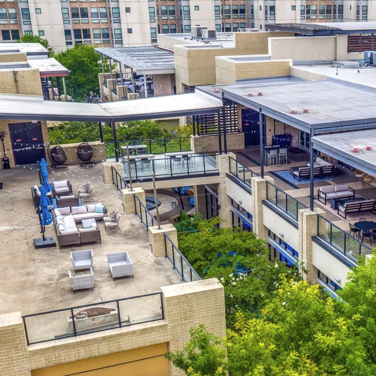 An aerial view of a multi-level commercial building with outdoor seating areas surrounded by greenery.