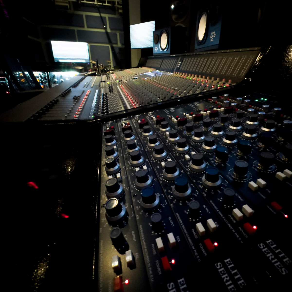 A close-up view of a recording studio mixing console with various knobs and sliders.