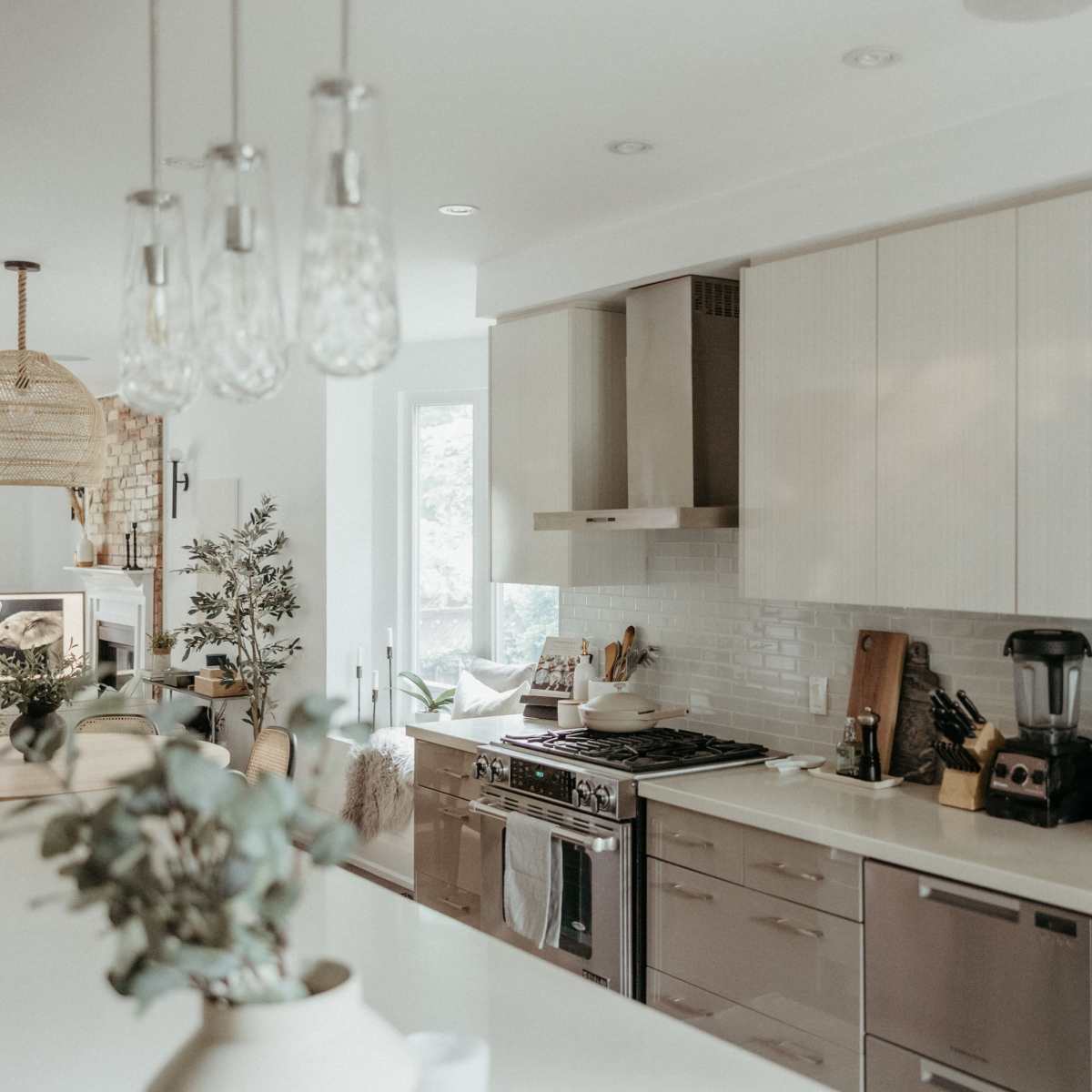 A modern kitchen features light cabinetry, a stainless steel stove, and a central island with seating.
