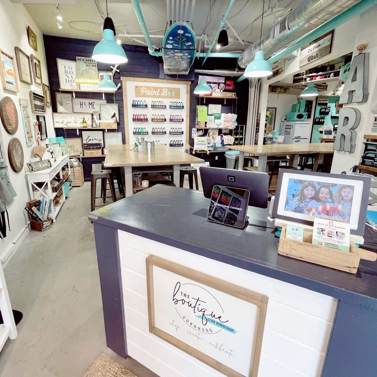 A colorful craft boutique featuring a service desk at the front, shelves of paint supplies, and various art pieces on the walls.