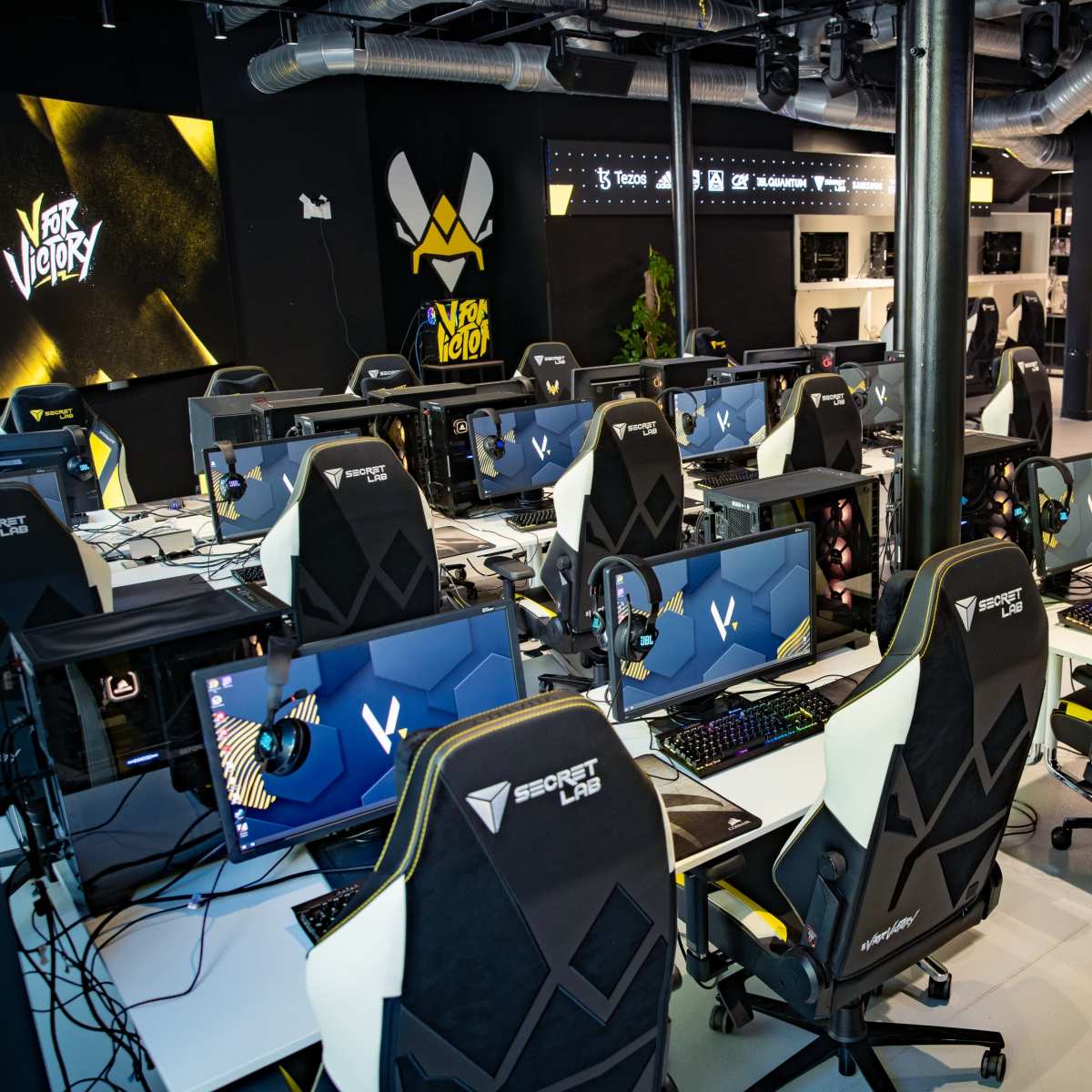 A modern esports facility featuring multiple gaming stations, each with a computer and ergonomic chair, arranged in an organized manner.
